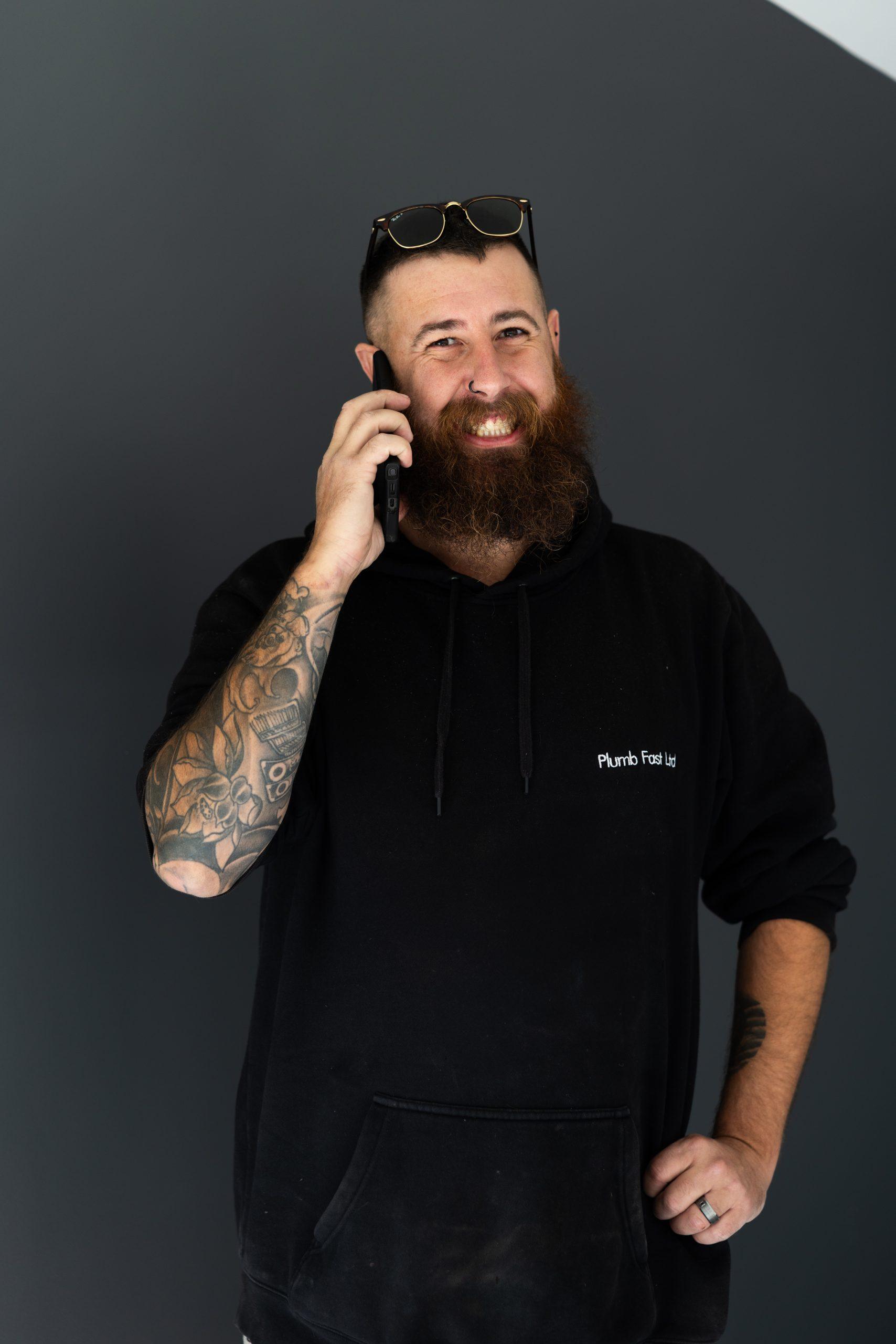 Plumbfast plumber in a branded hoodie taking a customer call