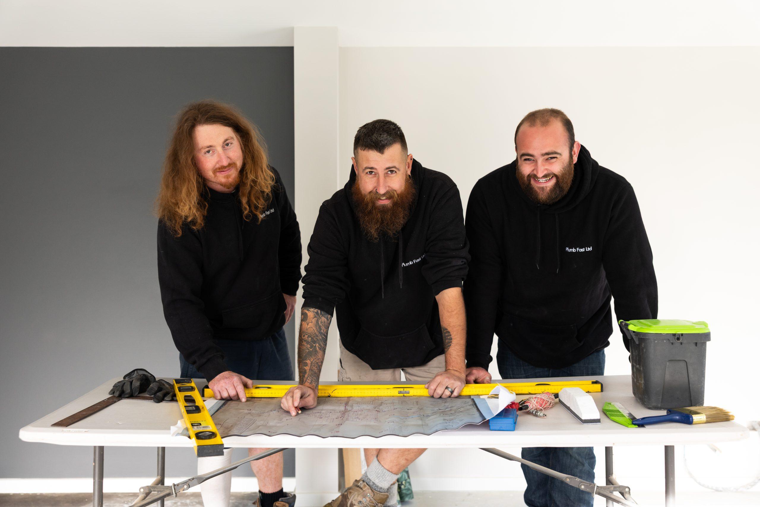 Three Plumbfast plumbers reviewing site plans on a work table